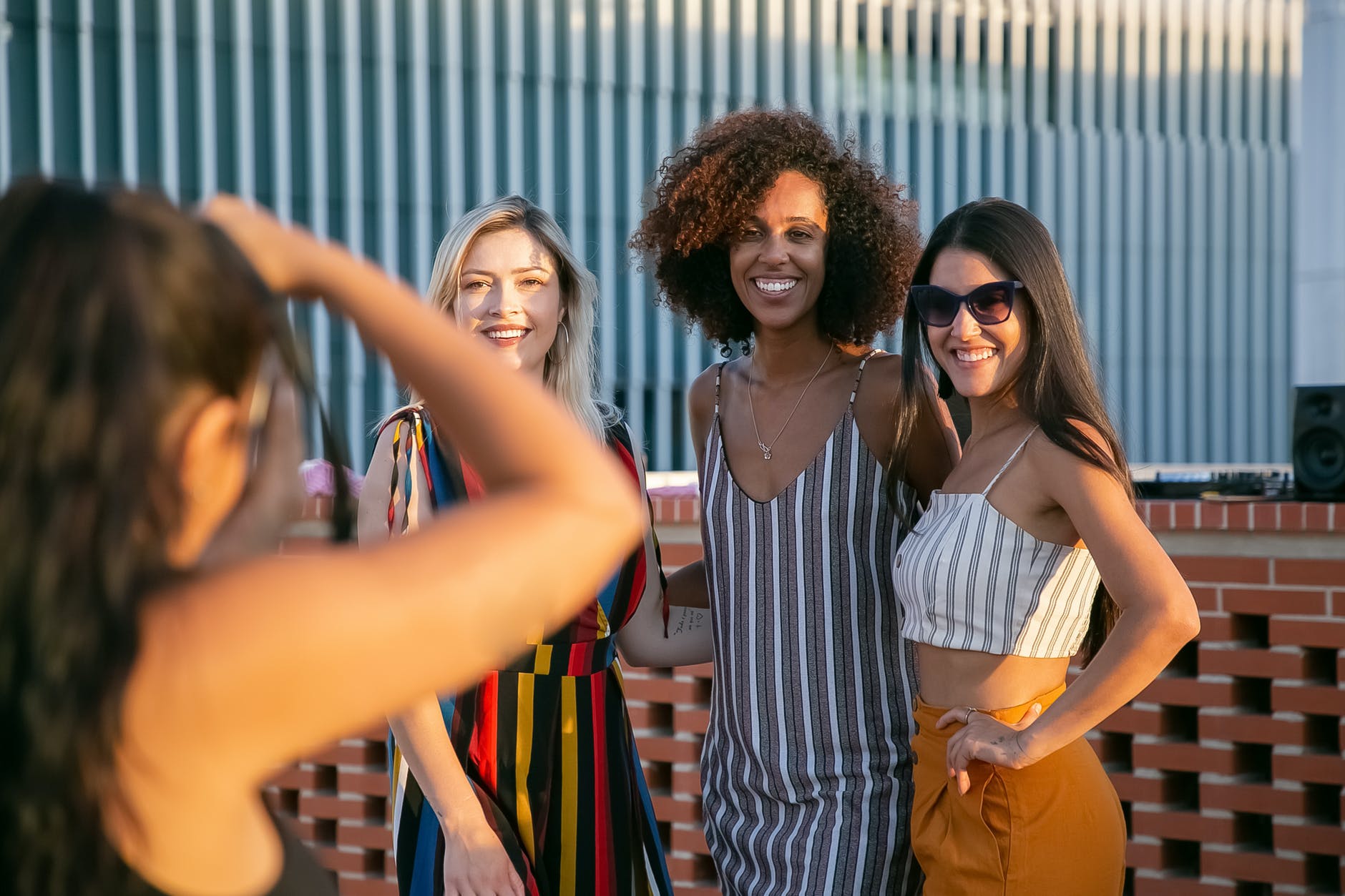 faceless woman taking photo of stylish female friends on terrace